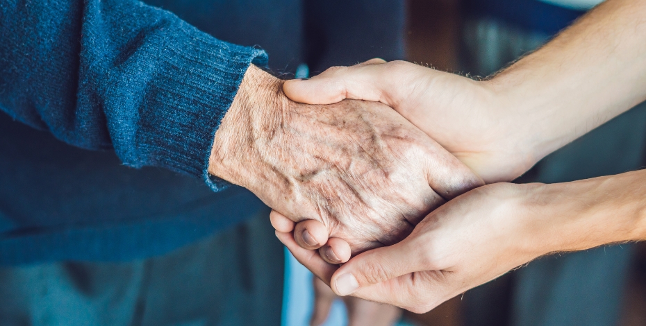 close up of hands holding each other one is the hand of an older person the other is the hand of a younger person
