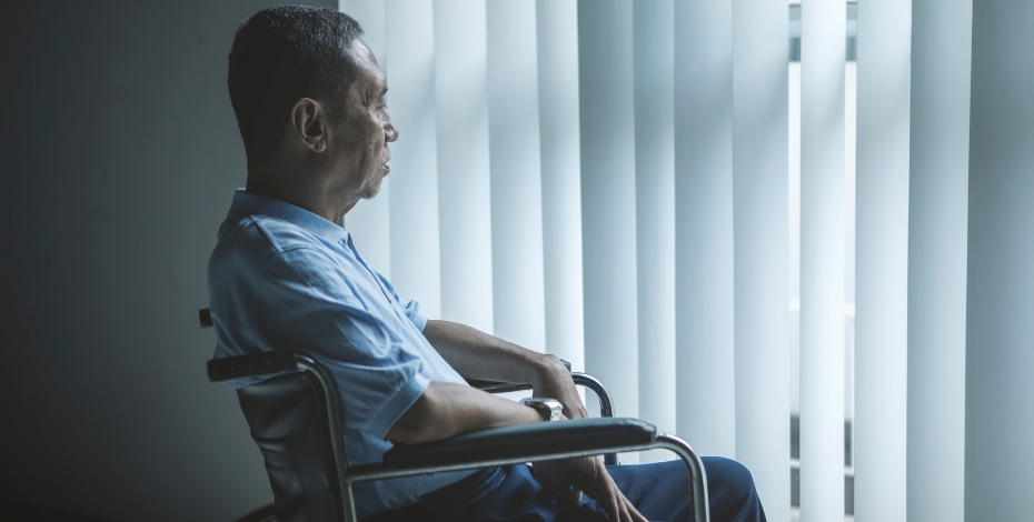 person in a chair looking through curtains to outside