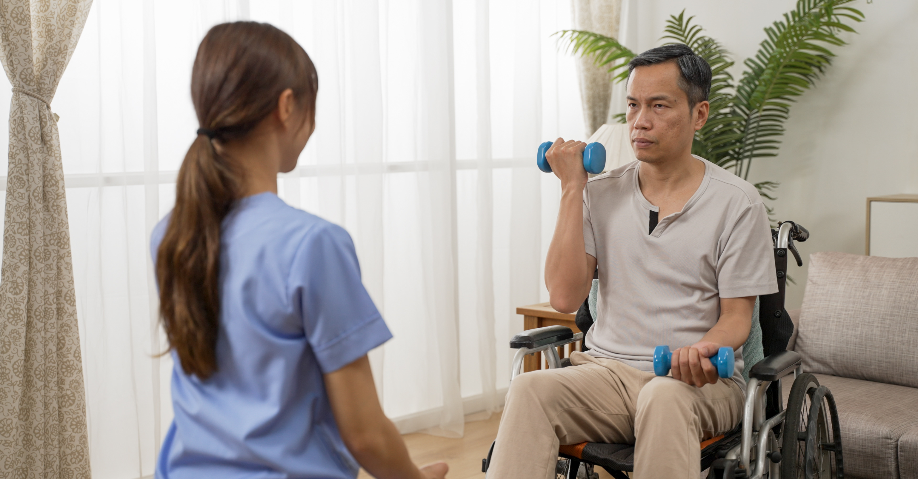 Person with a disability sitting in a wheelchair participating in an exercise program with small weights in their hands