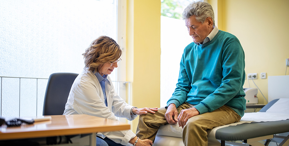 A doctor treats the knee of an older patient in the hospital setting.