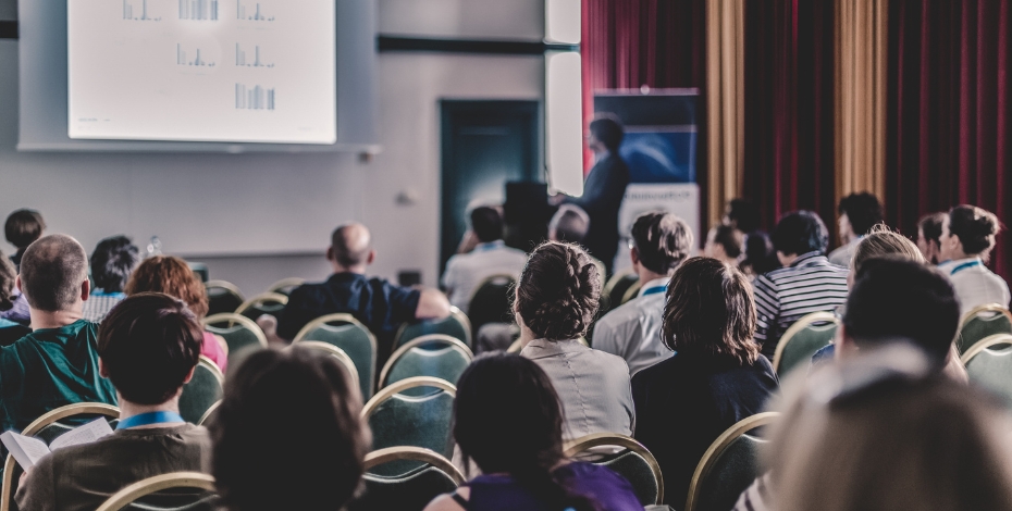people in a room watching a presentation at a conference or summit