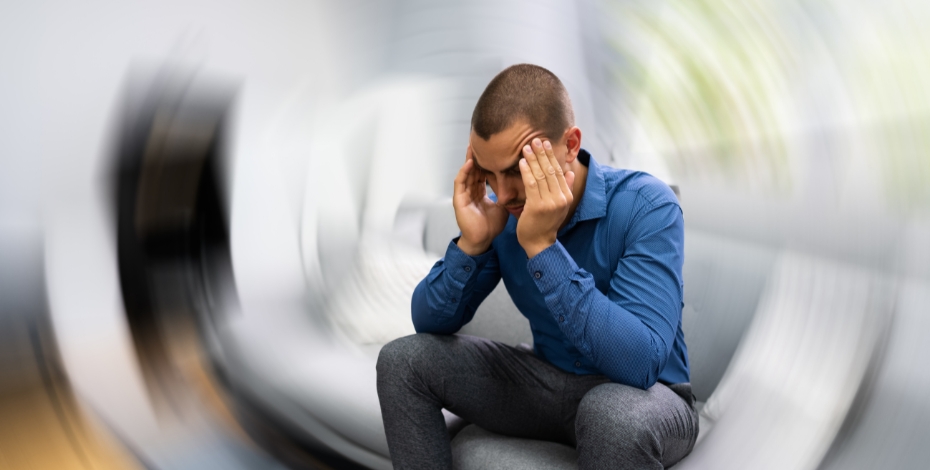 person sitting on a couch with their head in their hands and the room spinning around