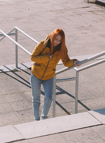 Woman struggles to walk up outdoor steps.